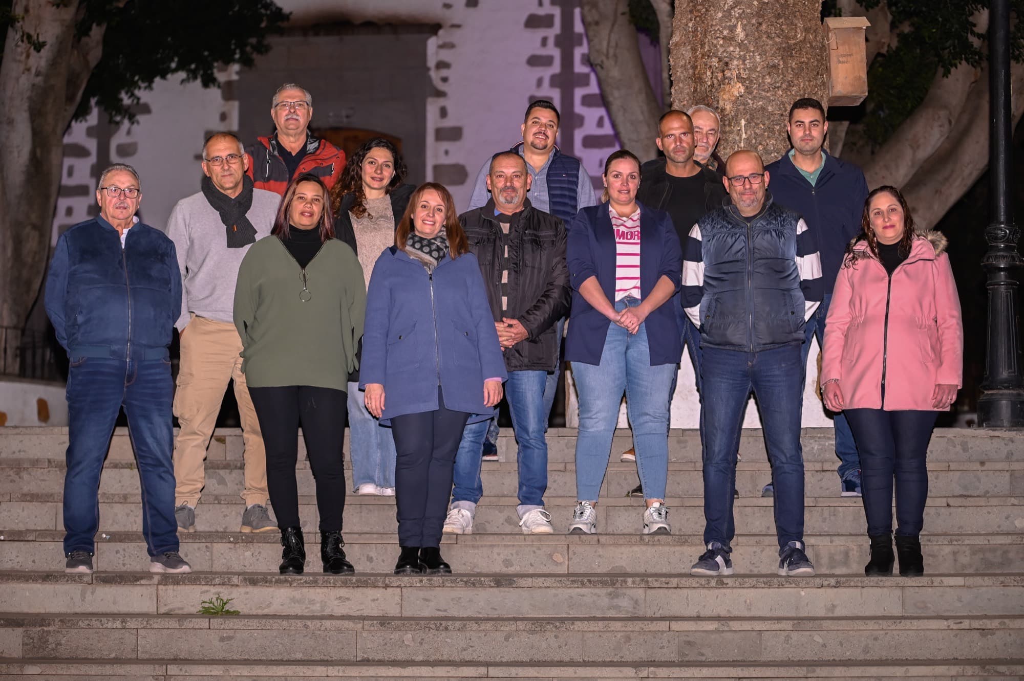 Grupo de una quincena de personas posando en las escaleras de un edificio de piedra, al aire libre.